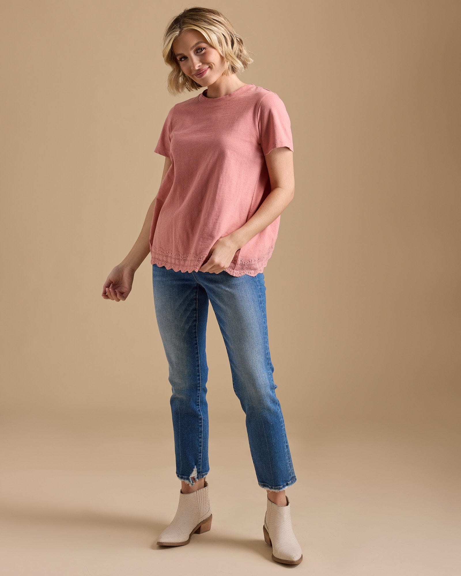 Woman in a pink short sleeve top with lace detail at hem