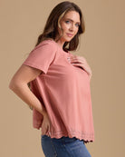 Woman in a pink short sleeve top with lace detail at hem