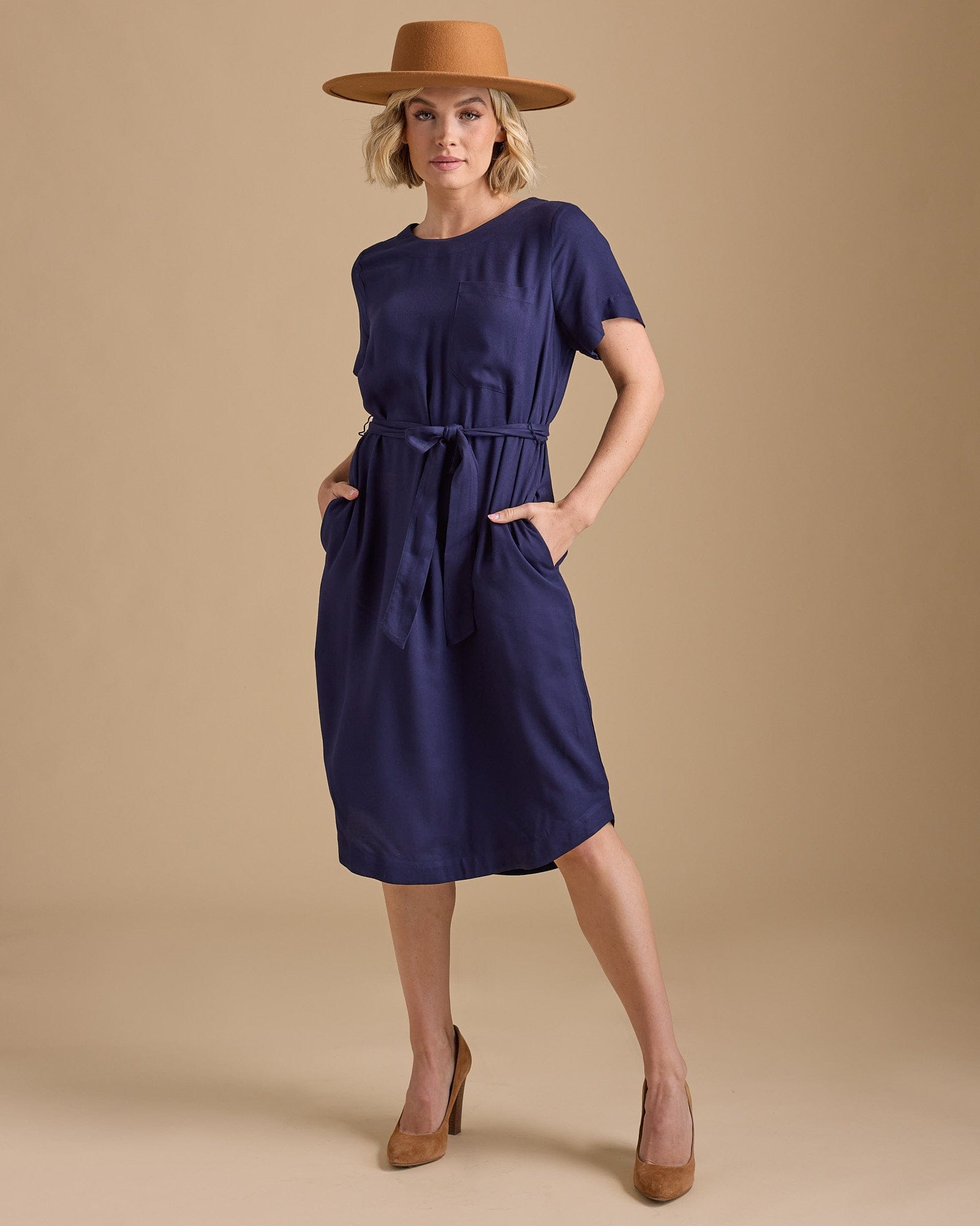 Woman in a short sleeve, knee-length navy dress with a tie at waist