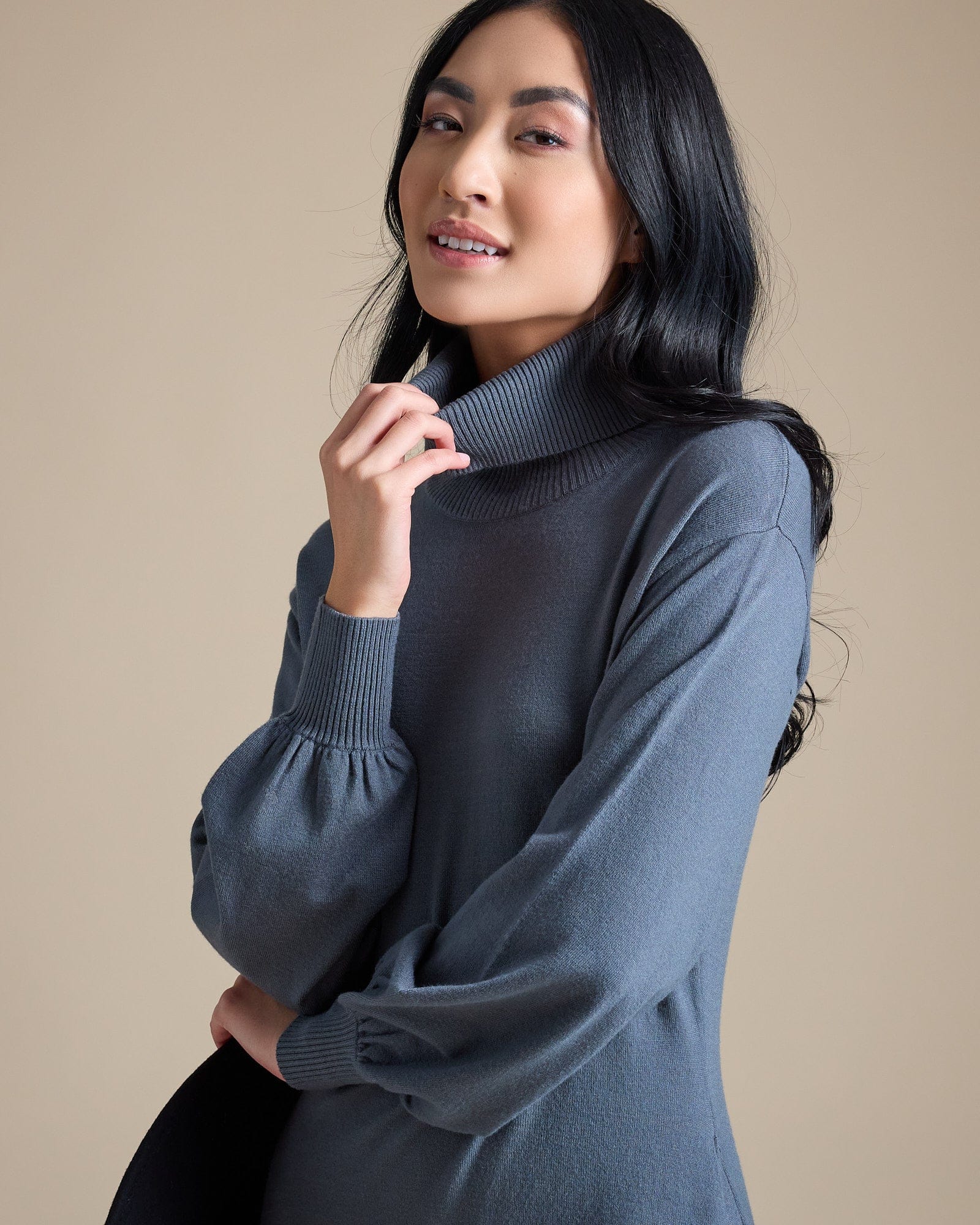 Woman in a long sleeve, midi-length, turtleneck, blue sweater dress